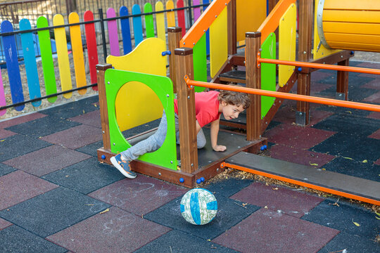 A little boy in a red shirt playing with a soccer ball on a colorful playground, enjoying a fun game and outdoor activity on a sunny day - Powered by Adobe