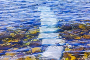 Protective bags on seabed between stones for safe entry on background of transparent water of Aegean Sea. Greece. Kos.