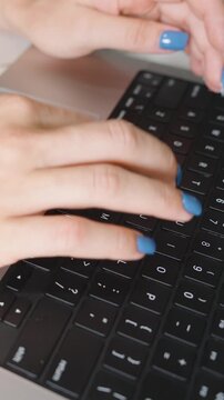 Vertical video. Close Up of Right Hand with Veins Visible Typing on Black Keyboard with Blue Nails