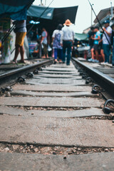 Railway track with people crossing it in a market in Thailand