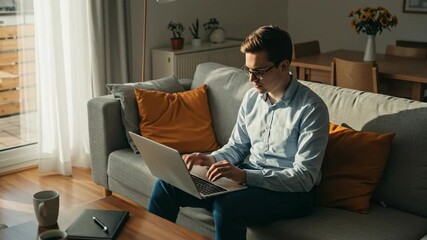 Focused Young Professional Working on Laptop in Cozy Home Office Environment with Natural Light and Comfortable Interior Design
