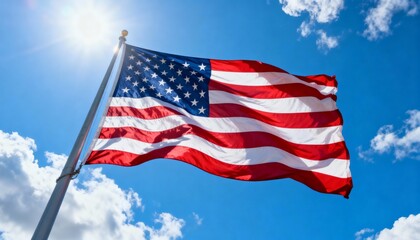 Fototapeta premium Low-angle view of large US flag waving under bright sky, emphasizing patriotism and grandeur