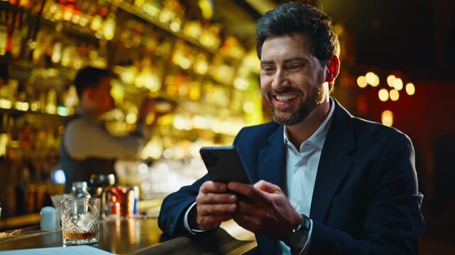 Laughing man chatting smartphone evening bar closeup. Guy scrolling cellphone 
