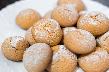 Close-up of homemade cookies dusted with powdered sugar on a white plate, sweet treat