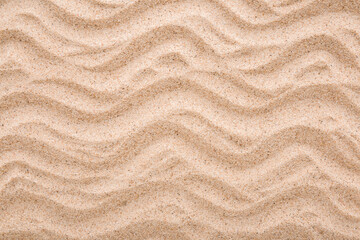 Dry light brown wavy sea sand background. Closeup. Top down view.