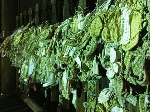 Sandalias tradicionales japonesas colgadas con etiquetas de deseos, composici&oacute;n artesanal con ambiente espiritual y tonos verdosos. Escena cultural detallada.
