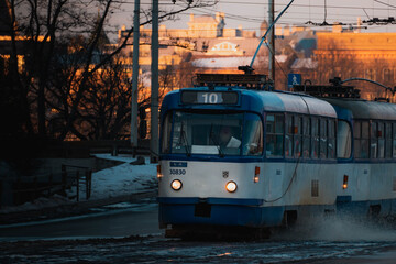 An old tram arriving at its stop, sprinkling snow from the rails.