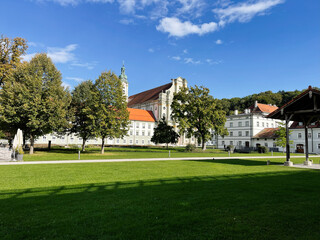 Historic Furstenfeldbruck German town square with church, red roofs, and lush green park under blue sky