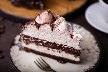 A piece of tiramisu cake with chocolate and whipped cream close up