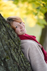 Portrait of a Girl in an Autumn Park in Coat and Red Scarf