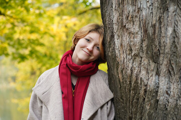 Portrait of a Girl in an Autumn Park in Coat and Red Scarf