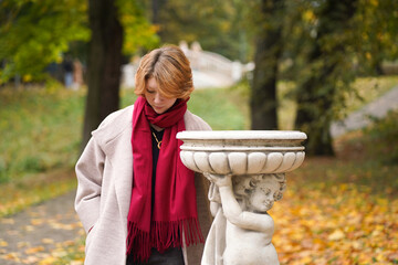 Portrait of a Girl in an Autumn Park in Coat and Red Scarf