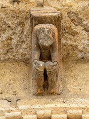 Romanesque stone corbel of a crouching bearded man at the Church of San Martin de Tours, Fromista, Spain
