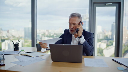 Concerned boss complaining smartphone call on document mistake in office closeup
