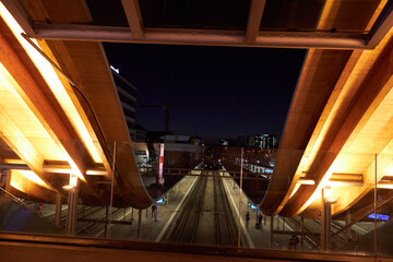 Estación ferroviaria moderna iluminada en noche urbana con arquitectura curva