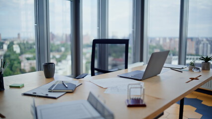 Empty corporate workspace laptop in office with city view. Workplace interior