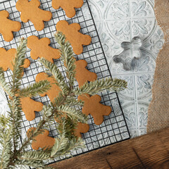 Freshly baked gingerbread cookies on black wire cooling rack on a white and gray textured tile surface.