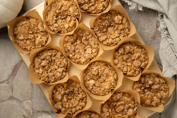 Fresh baked pumpkin cream cheese muffins with strudel topping wrapped in parchment paper cups