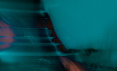 Dreamy moody cinematic portrait of a brunette woman with blue-green glow and long exposure