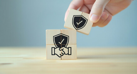 Wooden blocks with a handshake and a shield with a checkmark illustrate the importance of a trusting and secure business agreement.