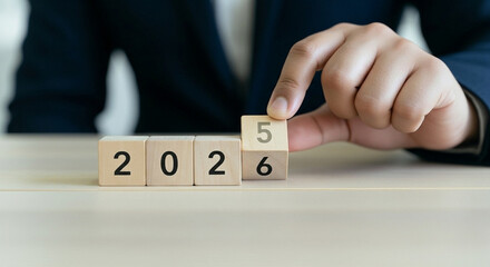 A person is shown completing the year "2026" with wooden blocks, representing a new business cycle, goal achievement, and time progression.