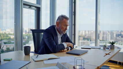 Aged entrepreneur feeling stress sitting workplace. Bearded businessman thinking