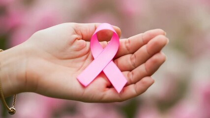 Woman hand holding pink ribbon sign for breast cancer awareness and charity donation event for patient health, footage.