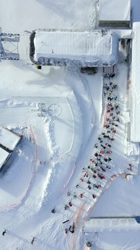 Aerial view of queue for ski lift at snowy winter resort. People in colorful gear waiting at the slope. Perfect for themes of skiing, tourism, winter sports, and mountain lifestyle.