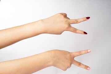 Two hands making a sideways V sign with two fingers against a white background