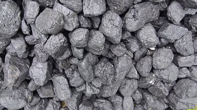 A pile of dark, lumpy coal gleams with a slight sheen, showing a rough, varied texture. Video 4k