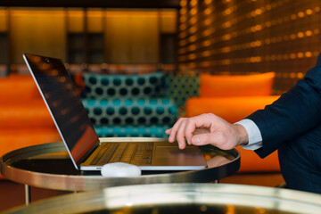 Modern finance and digital economy. A businessman working at a computer with focus on cryptocurrency and stock markets. Hands with laptop close-up.