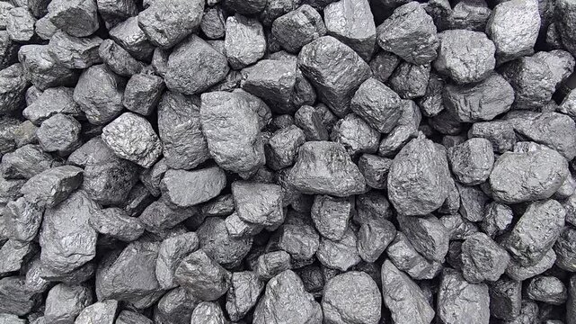 A pile of dark, lumpy coal gleams with a slight sheen, showing a rough, varied texture. Video 4k