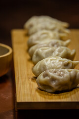 Raw and cooked Japanese gyoza dumplings on rustic surfaces – handmade Asian cuisine