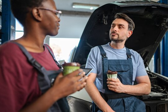 Mechanics taking a coffee break and discussing about car repair