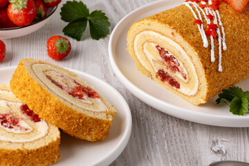 Delicious strawberry roll cake served on a wooden board with fresh strawberries in a white bowl in the background