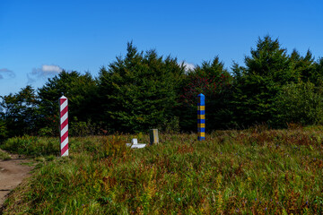 Sunny border meadow with Poland and Ukraine posts beneath blue sky
