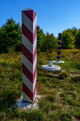 Polish and Ukrainian border posts on sunlit meadow beneath blue sky