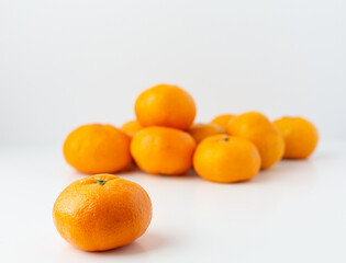 Close Up of One Tangerine with More Tangerines in the background on a White Background