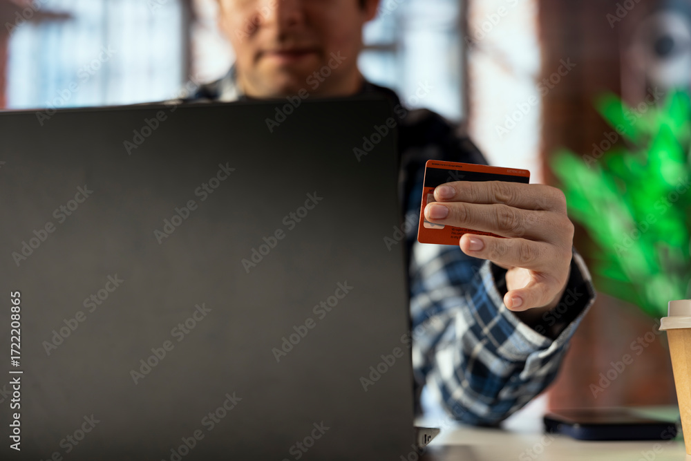 Aufkleber man doing internet shopping, typing credit card information on notebook, placing products in cart. c