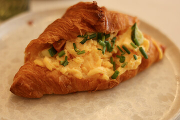 Croissant sandwich with poached egg, tomato and avocado on plate