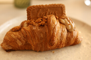 A lotus croissant cake on a white plate with a spoon and fork