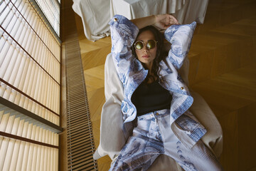 An effortlessly chic woman relaxes in designer resort wear, embracing a moment of calm.