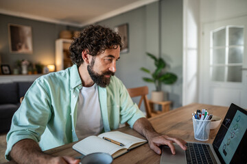 Fototapeta premium Man working remotely on laptop from home office