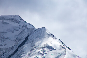 A close-up of a mountain peak in bad weather, leading to the death of climbers in windy weather, snow-capped peaks in the clouds