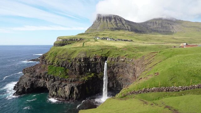 Waterfall plunges from a cliff into the ocean in the faroe islands