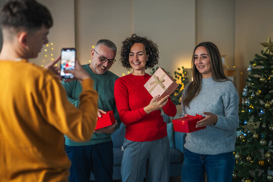 Young man recording family receiving christmas gifts on phone - Powered by Adobe