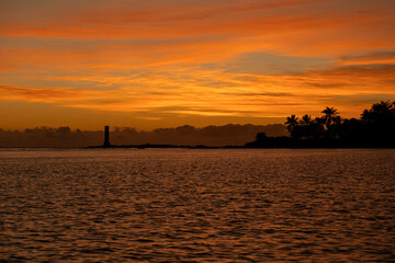 Naklejka premium Golden sunrise in Itacaré, Bahia, Brazil. Boats floating on calm sea, yellow light on the horizon, tropical coastal landscape with warm tones and natural beauty.