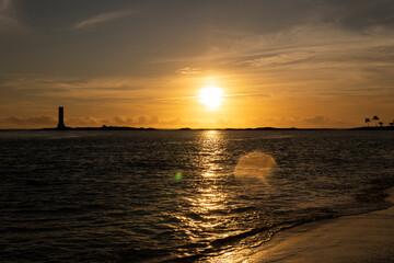 Naklejka premium Golden sunrise in Itacaré, Bahia, Brazil. Boats floating on calm sea, yellow light on the horizon, tropical coastal landscape with warm tones and natural beauty.