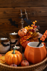A cozy autumn composition with orange pumpkins, decorative candles and fallen leaves. This scene creates a warm, festive Halloween atmosphere.
