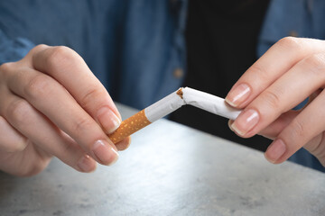 Woman hand holding a broken cigarette. Stop smoking.